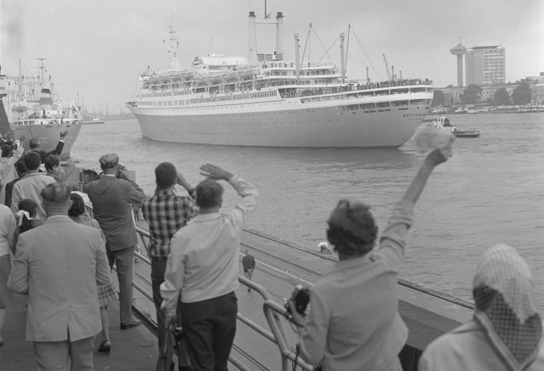 Zwaaiende mensen op de kade van de Holland Amerika-Lijn-vertrekhallen aan de Wilhelminakade. De ss Rotterdam vaart uit, 1968.Nummer uit collectie: NL-RtSA_4121_24162-1-14