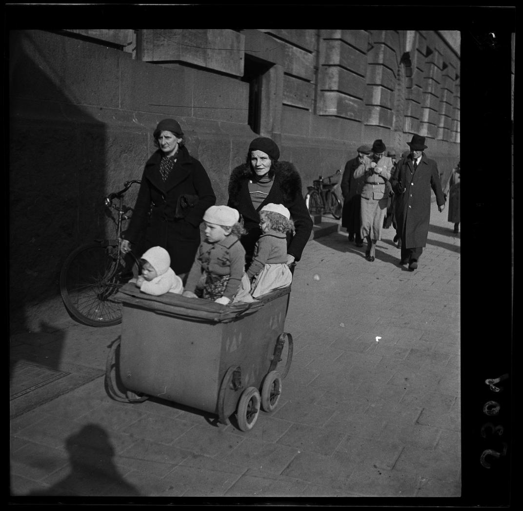 Een vrouw loopt met een kinderwagen met drie kinderen langs het postkantoor aan de Coolsingel. Foto uit de collectie Spaarnestad