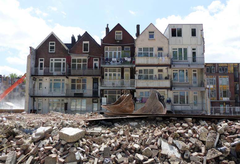 De sloop en vernieuwing van de Tweebosbuurt. Een rij te slopen woningen in de Tweebosstraat gezien vanaf de Hilledijk. Deze huizen worden tijdelijk bewoond door krakers. Op de voorgrond ligt een grote hoeveelheid puin, 27-5-2022. Collectie 4072, documentn